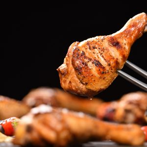 Grilled chicken leg with various vegetables on the grill